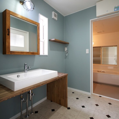 温かい木材を使用したアンティーク調の洗面化粧台。鏡は開閉できる収納スペースに。