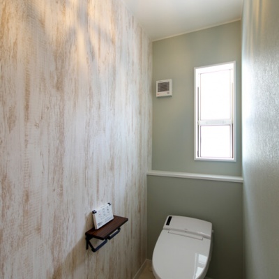 白を貴重とした木目調のクロスで明るいトイレ